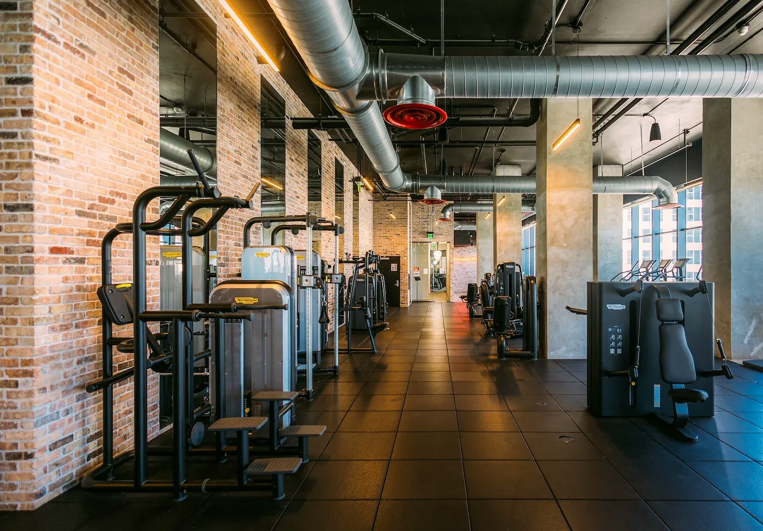 An apartment fitness center with weight machines and high ceilings