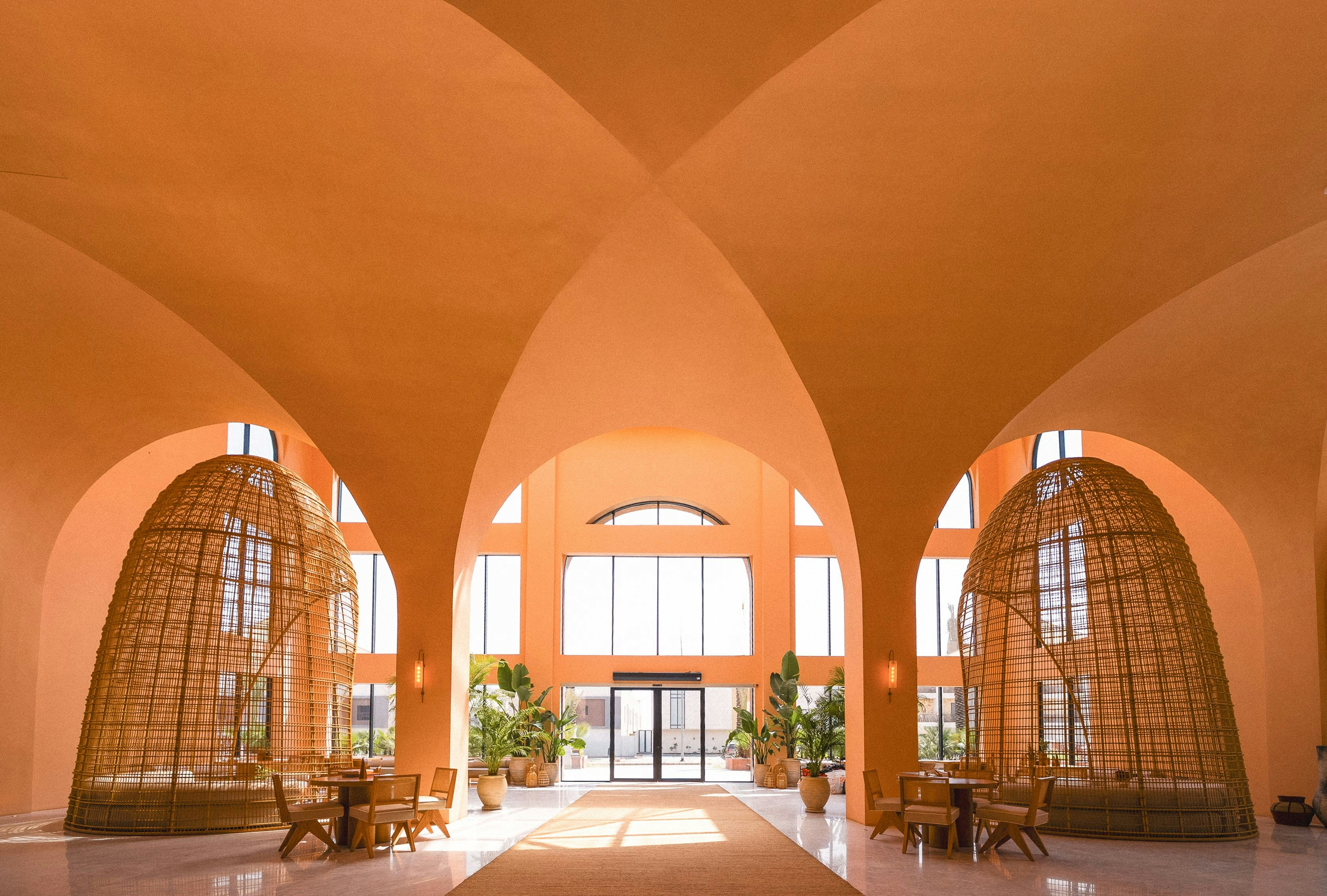A large apartment lobby with wooden furniture and semi enclosed wicker seating domes