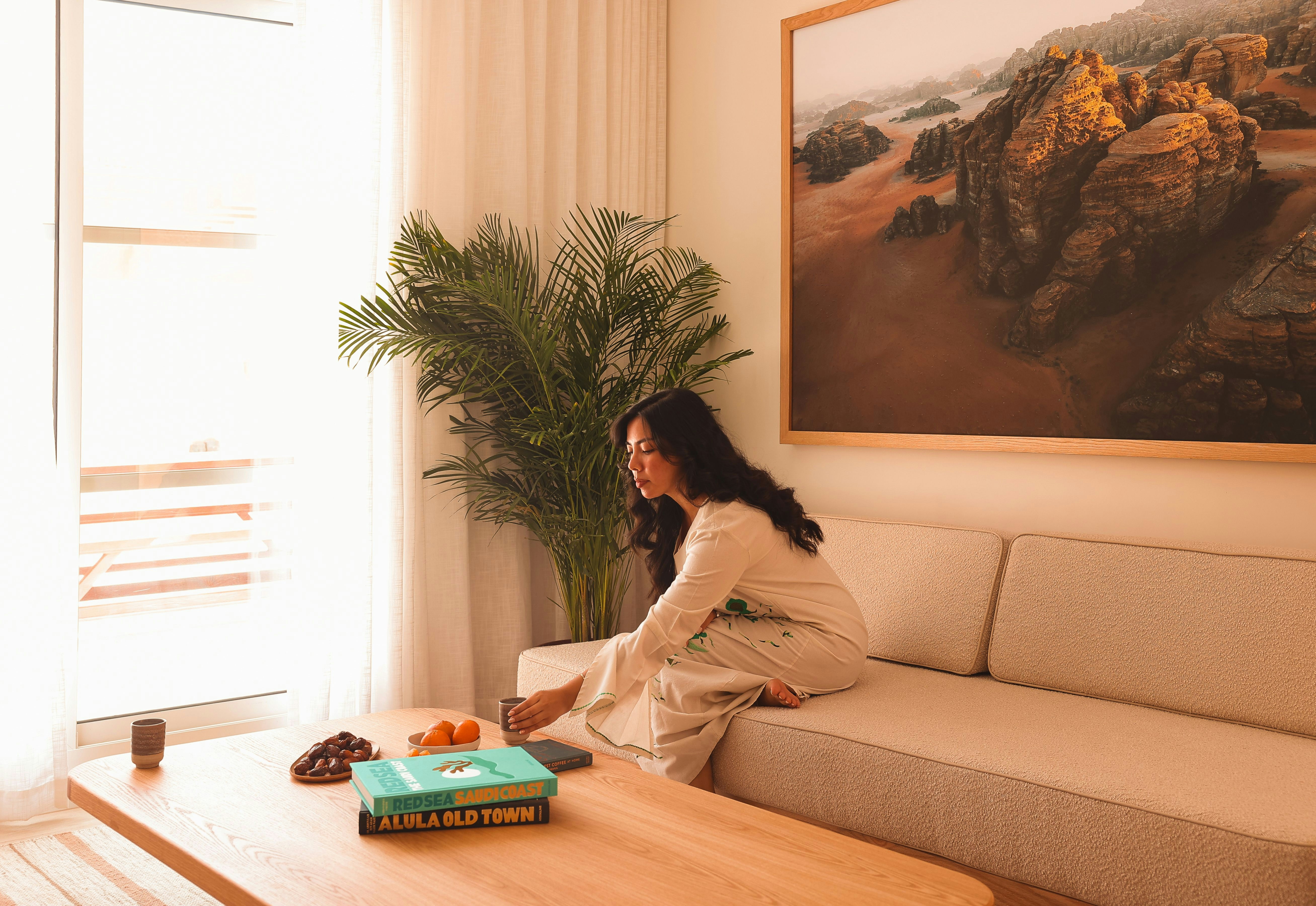 A woman reaches a mug from a sofa in a luxury apartment living room
