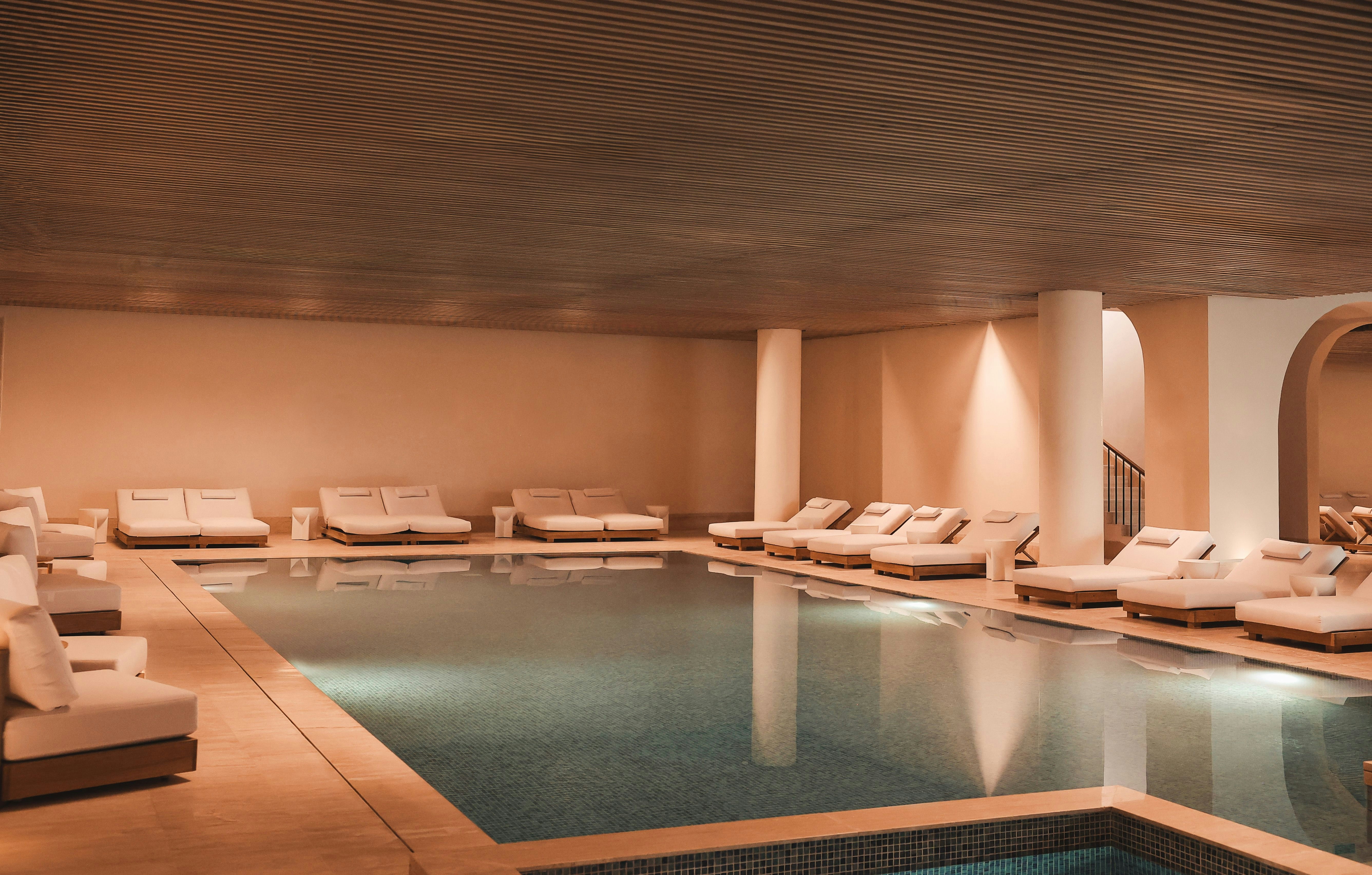 A large indoor pool surrounded by beds next to two hot tubs 