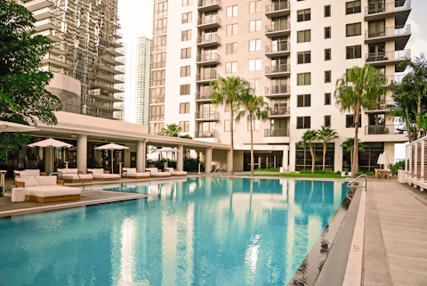 Sunset view of luxury pool surrounded by palm trees and loungers