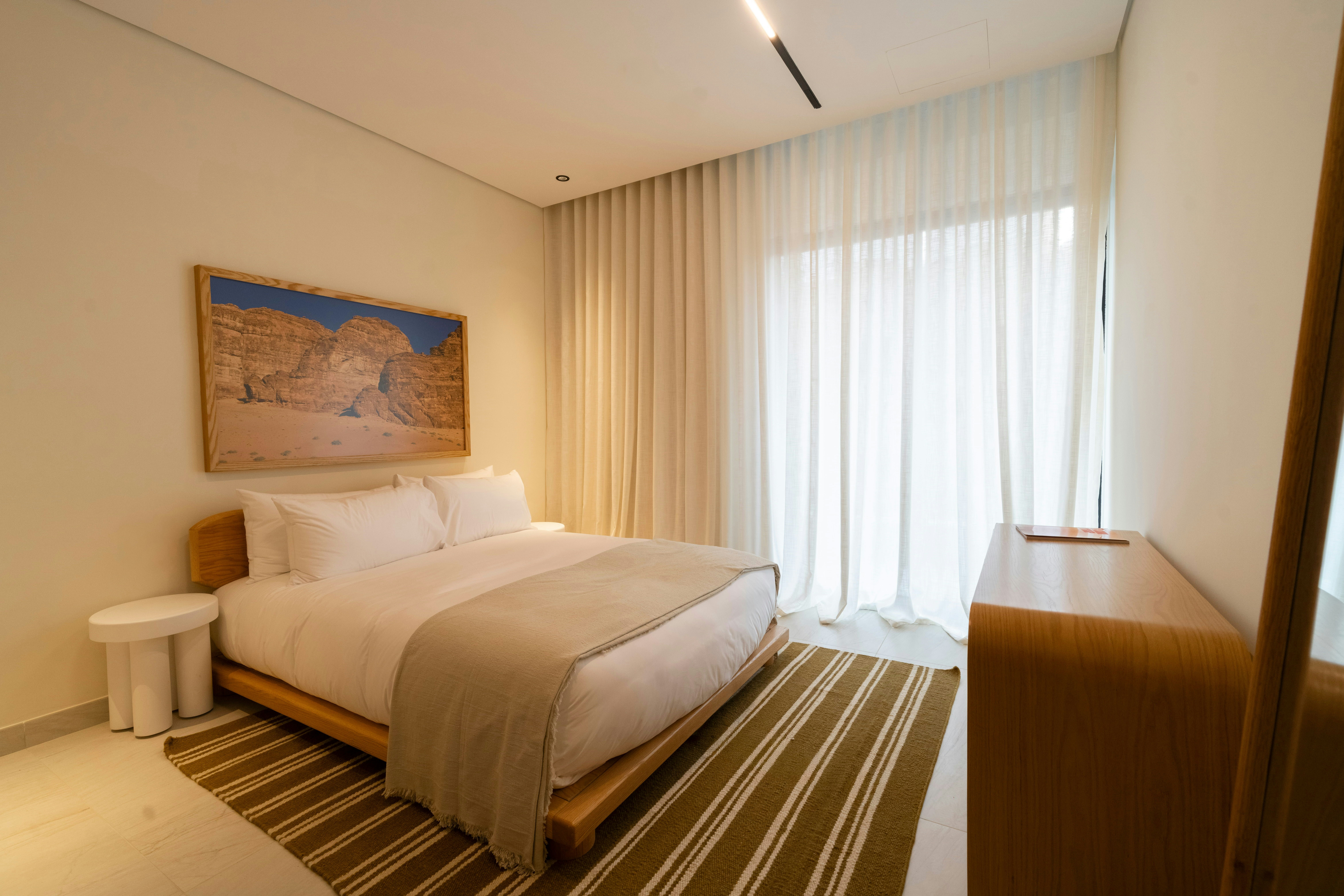 A large bedroom next to closed curtains and artwork