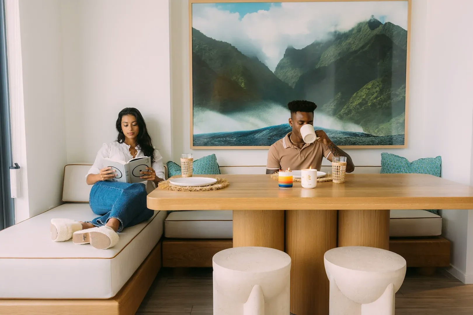A man and a woman sit at a dining room table and chaise lounge in a luxury apartment dining room